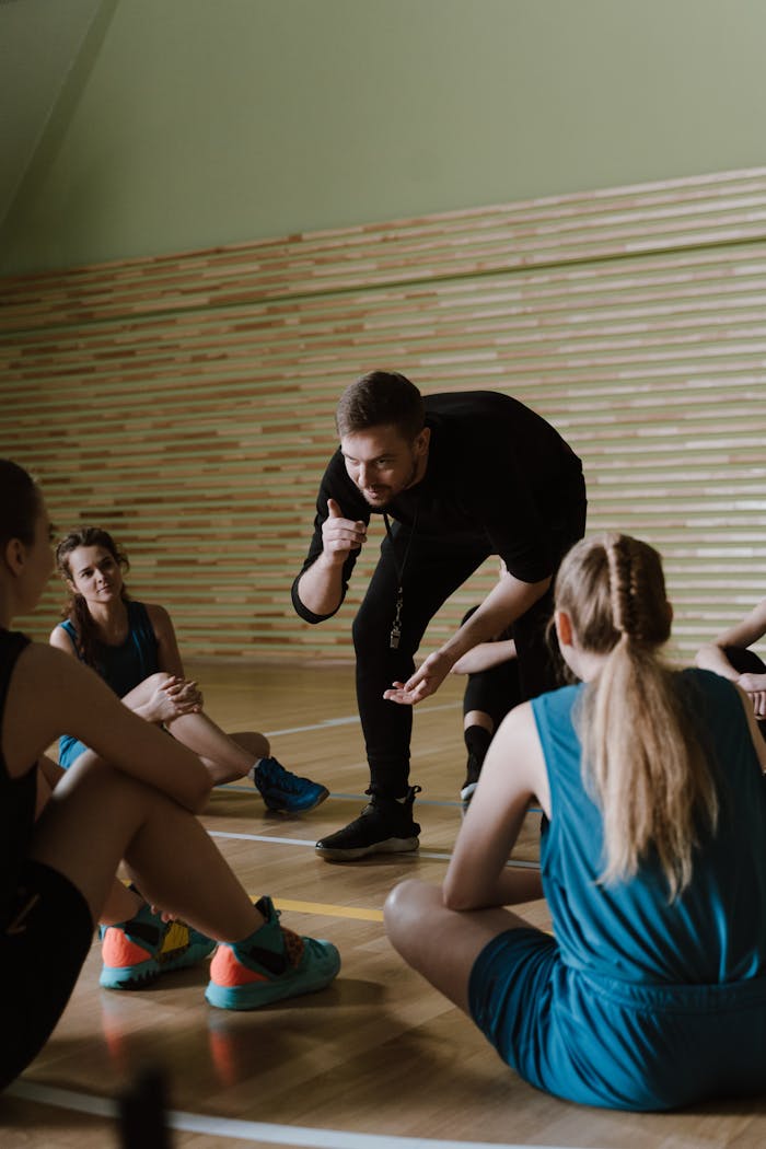 A group of female basketball players receiving guidance from a coach indoors.